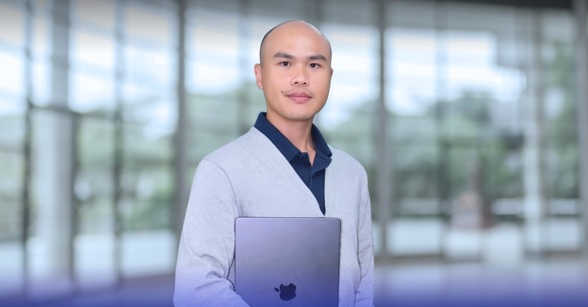 project-manager-at-724edu-standing-in-front-of-a-glass-facade-office-building-holding-a-macbook